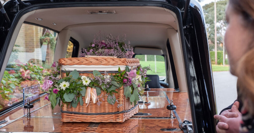 A casket adorned with flowers sitting in the back of a hearse.