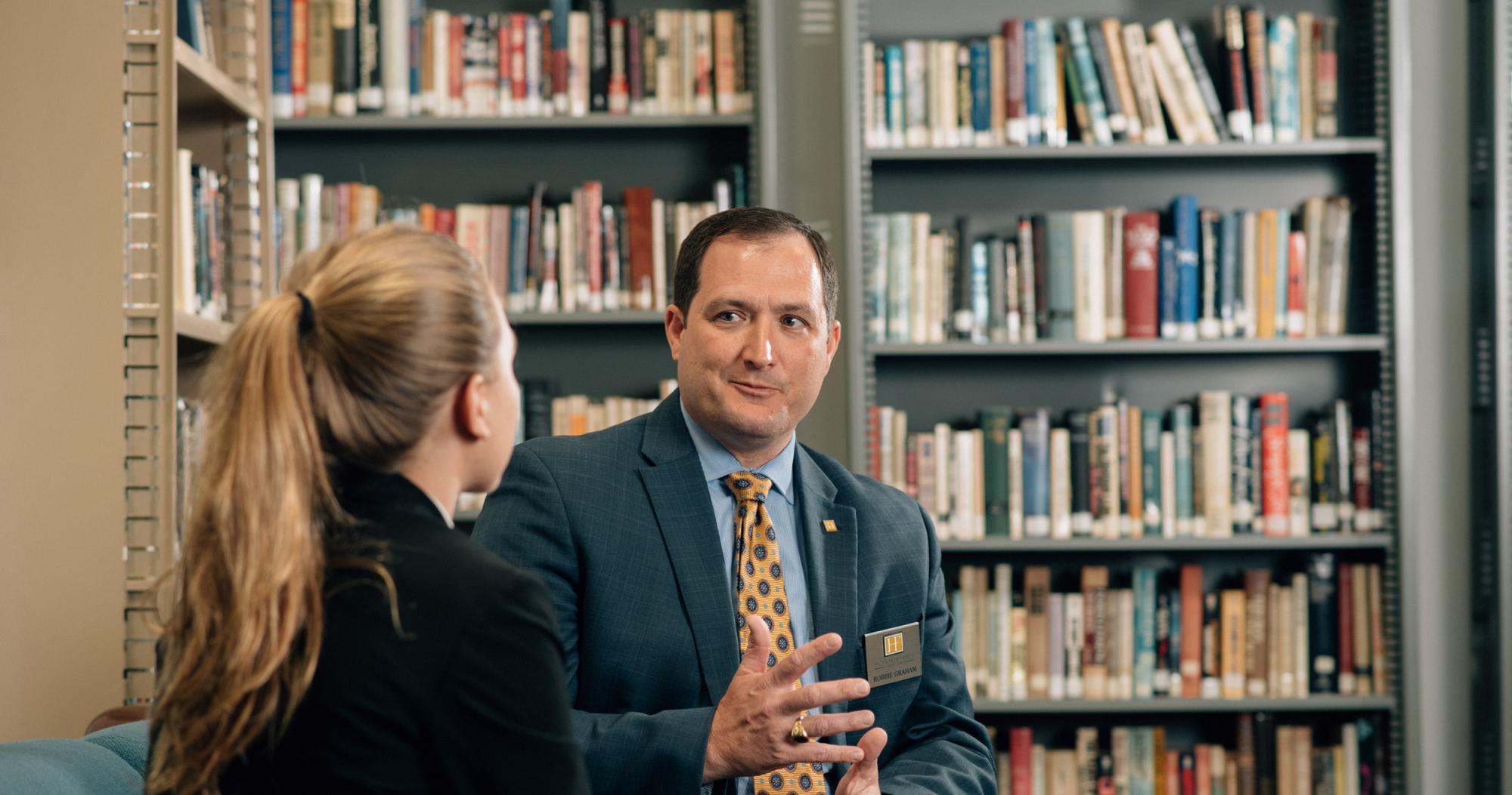 Professor and student engaging in conversation in a library