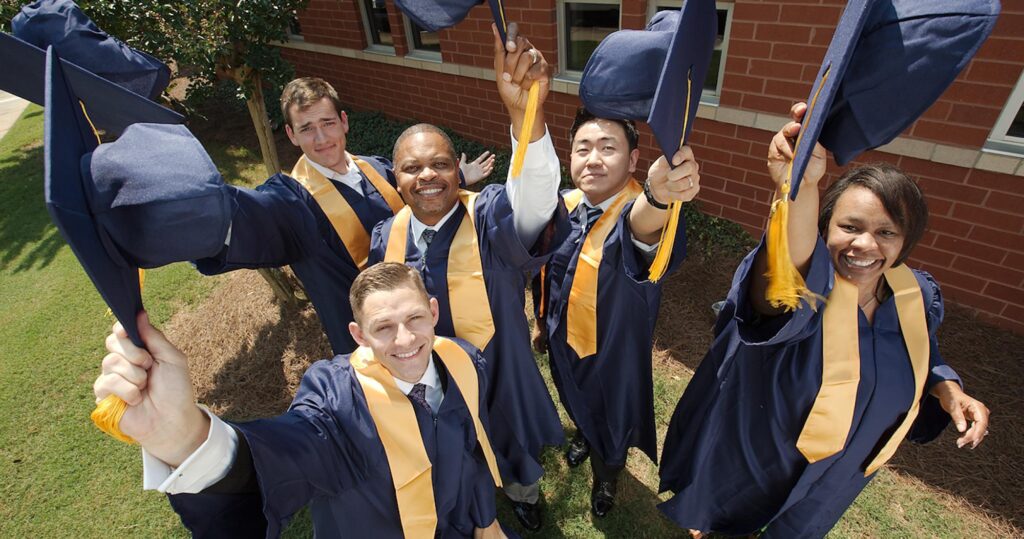 A downward view of happy graduating students tossing their caps upwards in victory